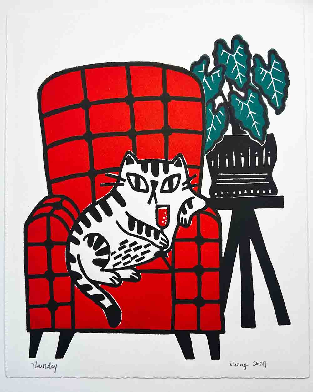 cat holding wine on a red chair with plant